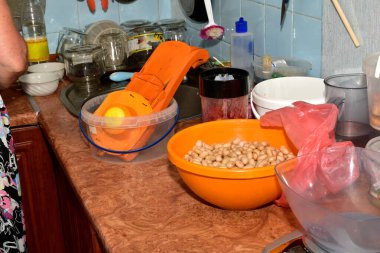 Resimde mutfakta içinde bir kase haşlanmış fasulye ve sebze keskisi olan bir masa var..