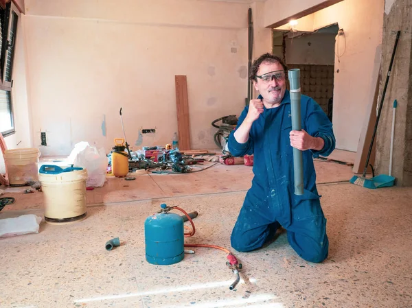 Fontanero en un sitio de construcción de cocina, trabajando con tuberías de PVC . — Foto de Stock