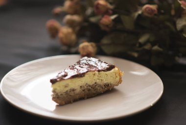 Parça çikolatalı pasta plaka üzerinde ve siyah arka plan üzerine çiçek