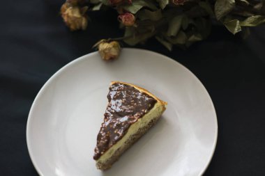 Siyah arka plan üzerine çikolatalı cheesecake ve çiçek üstten görünüm