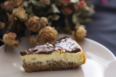 Cheesecake ile siyah arka plan üzerine çikolata ve kurutulmuş gül çiçek