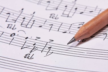 Kahverengi kalem yanındaki el yazısıyla yazılmış müzik sayfası
