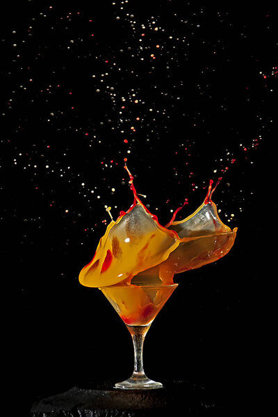 Orange cocktail glass splashing. Frozen movement. Black background.