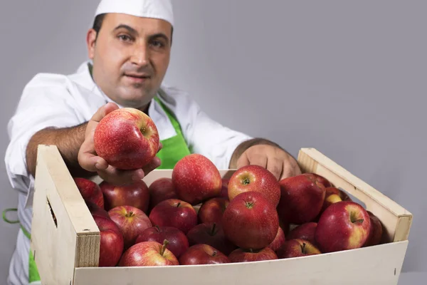 水果销售商与绿色围裙提供一个红色的苹果 — 图库照片