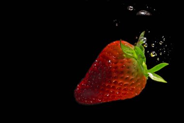 Çilek siyah arka plan üzerinde kabarcıklar ile suya batırılmış