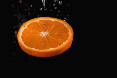 Turuncu dilim siyah arka plan üzerinde kabarcıklar ile suya batırılmış