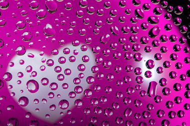 Birçok su damlasına yansıyan pembe bir balonun üzerindeki beyaz kalp.