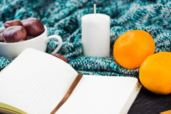 Home comfort with notepad. Around comfort, candle, tangerines, chestnuts