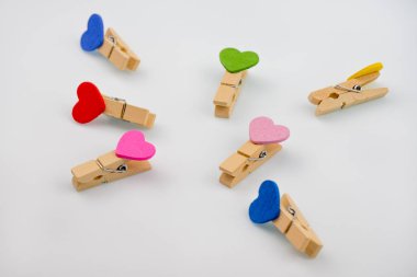 Küçük clothespins ile beyaz bir arka plan üzerinde kaotik bir şekilde yüzeyinde dağınık kalpler