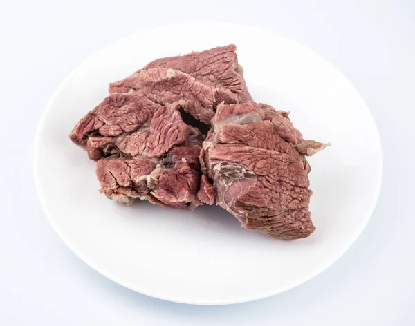 Boiled lean meat, close-up, in a large white plate, the background is white blurred
