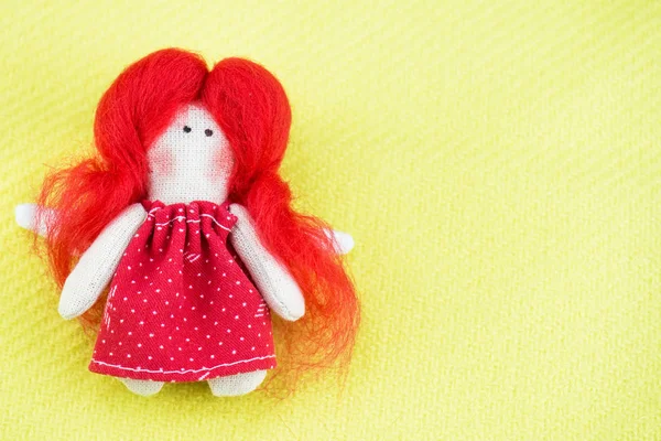 A small handmade rag doll, an angel, lies on an olive fabric. Background blurred