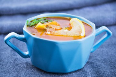 Kırmızı mavi bir tabak çorba. Yakın çekim. Gri kumaş arka plan