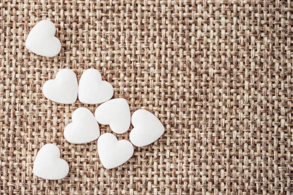 White small hearts pills scattered on the fabric, natural flax, large weaving