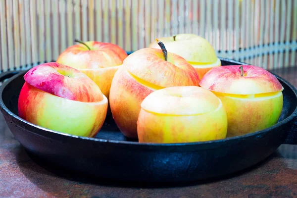 Frying pan close-up. In the pan, fresh apples prepared for baking in the oven. In the background is a bamboo mat, blurry