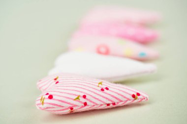 Hassas yastık kalp güzel bir kumaştan dikilir. Yan görünüm, kalp çapraz, yakın çekim üzerinde üst üste yatıyor. Arka plan ekran koruyucu, arka plan zeytin, bulanık