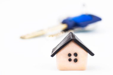 Plastik ev kapatın. Arka planda, metal halka üzerinde dairenin anahtarları bulanık. Arka plan beyaz, bulanık