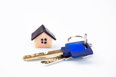 Daire ve küçük bir ev, plastik anahtarları yakın çekim. Arka plan beyaz, bulanık. Boşaltmak imzalamak için bir yer var.