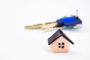 Küçük plastik ev, yakın çekim. Arka planda, dairenin anahtarları bulanık. Arka plan beyaz, bulanık. Boşaltmak imzalamak için bir yer var..