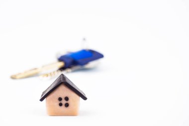 Plastik ev simge sol alt köşesinde kapatın. Arka planda, dairenin anahtarları bulanık. Arka plan beyaz, bulanık