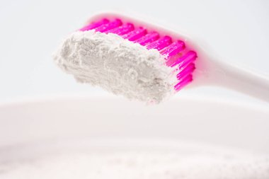 Bir diş fırçası closeup. Fırça Diş tozu ile kıllar. Arka planda bir kavanoz Diş tozu var. Arka plan beyaz