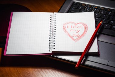 Tablo, üstten görünüm, yakın çekim bir laptop dizüstü bilgisayar. Bir kalp ile bir yazıt Notebook - işimi seviyorum. Üzerine kırmızı kalem ise