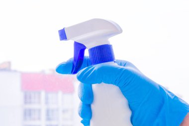 Lastik eldiven elinde bir pencere, closeup yıkar. Kavramsal temizlik ürünleri kullanma pencere temizleme. Bulanık şehir dışında. Açık renkli