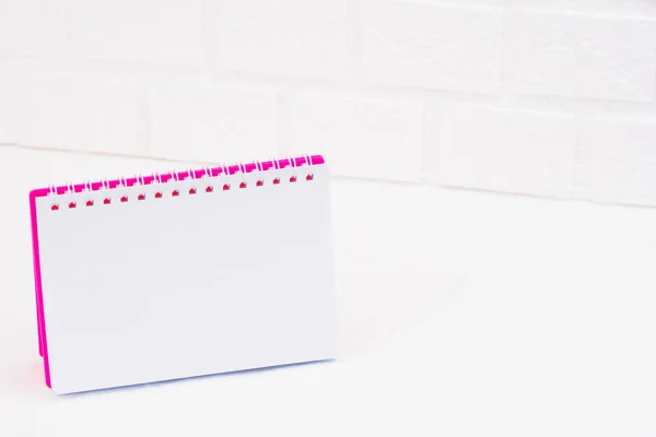 Notebook for signature in a pink cover is open and stands on a light brick wall background