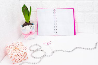 Dünya Kadınlar gününde romantik selamlar. Vintage sarmalayıcı bahar çiçeklenir. Bir tencerede beyaz sümbül. Hediyeler şenlikli ambalaj kutuları. Defter pembe bir kapak ile imza için bir yer yoktur. Gümüş boncuk kaplı 8 bul. Kavramı o