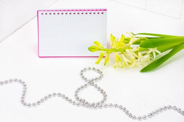 Uluslararası Kadınlar Günü tebrik ediyorum. Beyaz bahar çiçekleri, sümbül. Defter bir pembe kapak bir yer imza için. Şekil 8 yüzeyi gümüş boncuk ile dışarı atılır. Bahar tatil kavramı üzerinde Mart 8. Backgrou