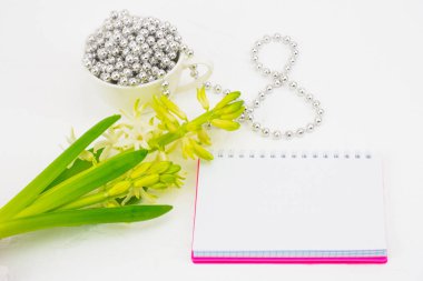 Uluslararası Kadınlar Günü tebrik ediyorum. Beyaz bahar çiçekleri, sümbül. Defter bir pembe kapak bir yer imza için. Şekil 8 yüzeyi gümüş boncuk ile dışarı atılır. Bahar tatil kavramı üzerinde Mart 8. Backgrou