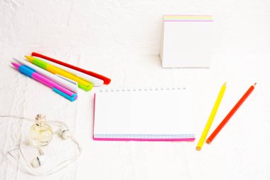 Office kavramı. Kulaklık telefon ve kırtasiye, hafif bir arka plan üzerinde renkli kalemler yazma, çıkartmalar, kadın parfümü bir paket imzalamak için defter iş kadını. Yakın çekim