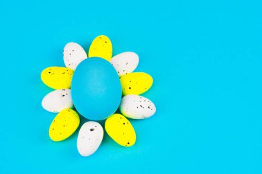 Paskalya tatil kavramı. Tepesinde güneş şekilli dekoratif Paskalya yumurta natürmort. Boyalı yumurta ile şenlikli ruh hali. Arka plan mavi