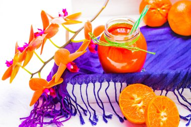 Portakal suyu çiçek aranjman arka plan üzerinde. Lila Tekstil vintage bir tepsi ve bir bardak içki. Açık renkli