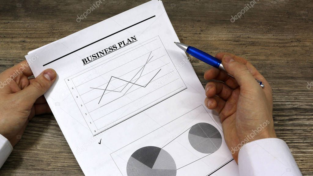 Job with finances in the office on a laptop,the employee holds paper with the inscription business plan.Businessman analyzes the chart of the rise or fall of prices and is a plan of action.business ideas	