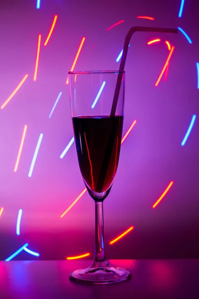 A glass on the bar in a cafe, restaurant, nightclub or disco. Glass or stemware with alcohol or a cocktail on a colored background. — Stock Photo, Image