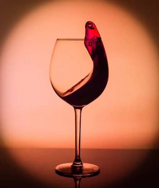 Un bicchiere di vino con una spruzzata di vino su sfondo giallo. Un bicchiere al bar in un caffè, ristorante, discoteca o discoteca . — Foto Stock