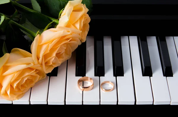 Желтые розы с обручальными кольцами на пианино. Готовлюсь к свадьбе. Подарок вашей возлюбленной на свадьбу или День Святого Валентина. Букет желтых роз, лежащих на пианино с обручальными кольцами . — стоковое фото