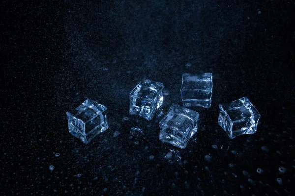 스플래시와 물방울이 있는 검은 색 배경의 얼음 조각. — 스톡 사진