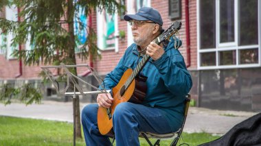 02 / 06 / 2020: Yoldan geçen insanlara gitar çalan bir sokak müzisyeni. Sokakta gitar çalan yaşlı bir adam halk için popüler müzik çalıyor..