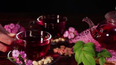 Çaydanlıktan çay dök ve cam bardaktan iç. Cam bardakta kırmızı amber çayı. Çay saati: çay, çarşaf, karkade, rooibos. Doğulu, samimi, tören, gelenek, Japonca, yapraklı, hygge