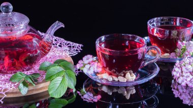 Çay saati: bir fincan çay. Amfibik çay ve yapraklardan oluşan yaratıcı bir düzen. Kırmızı çay, carcade, karkade, rooibos. Doğulu, samimi, tören, gelenek, Japon, yapraklı, kızlık zarı, sonbahar, saat 5 yönünde.