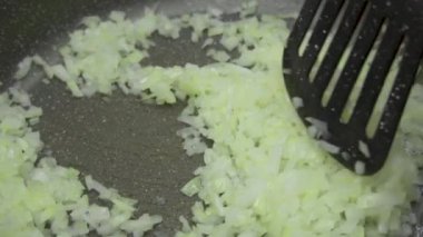 Kızartma tavasında taze soğanları spatulayla karıştırıp pişirirken yavaş çekim videosu. Pişirme, vejetaryen yemekleri.