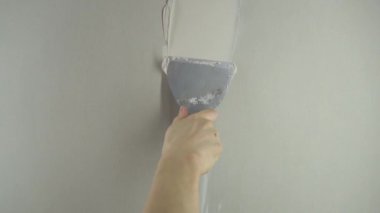 Bir işçi duvarı spatulayla kaplıyor ve çimento karışımı solüsyonu uyguluyor. Tamirci alçıpanı alçıpan üzerine serer. Tamirci evi tamir ediyor. İşçi konutları restore ediyor. Uzman çatlakları kapatıyor.