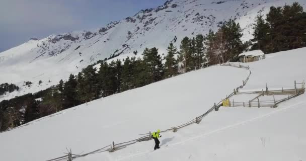 Человек в желтом поднимается в горах — стоковое видео