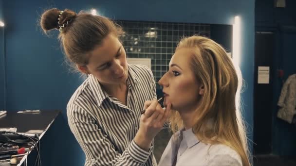 Professional makeup artist putting cosmetics on blonde model face — Stock Video