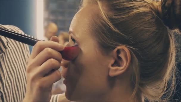 Profesionální make-up umělec uvedení kosmetiky na blond modelu obličeje — Stock video