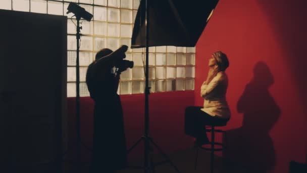 Φωτογράφος φωτογραφίζει ένα γυναικείο φωτογραφικό μοντέλο σε στούντιο — Αρχείο Βίντεο