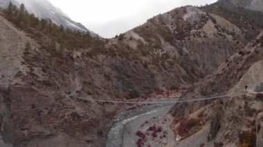 Dağ bisikletçileri Nepal 'de sallanan bir köprüden geçiyorlar..