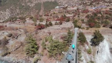 Dağ bisikletçileri Nepal 'de sallanan bir köprüden geçiyorlar..