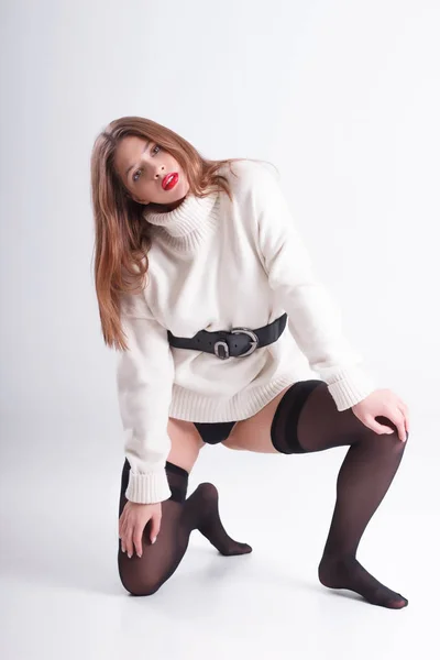 검은 스타킹, 흰색 스웨터에 그의 무릎에 서 있는 흰색 배경에 스튜디오에서 아름 다운 소녀 스톡 사진